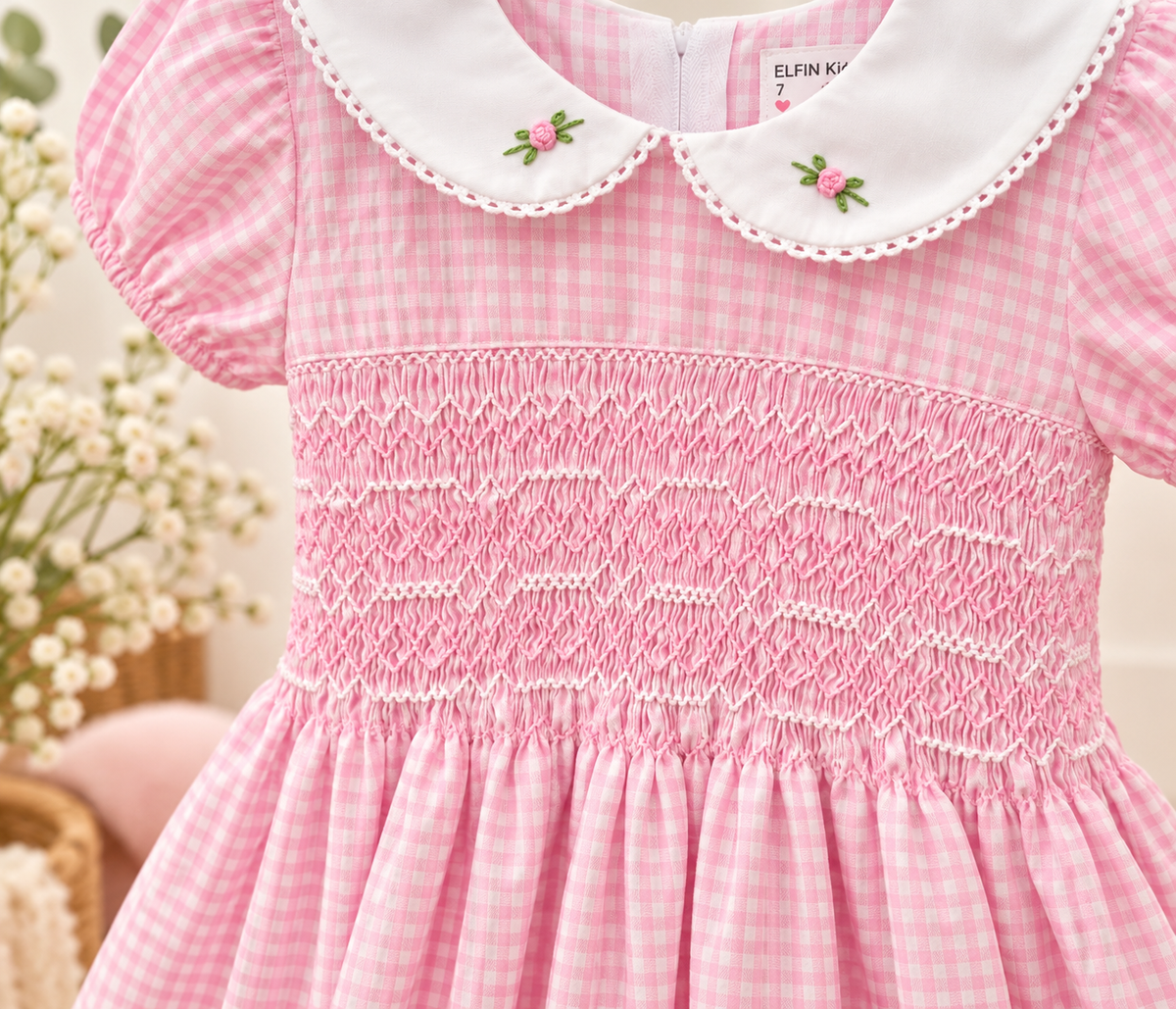 Close-up of pink gingham hand-smocked girls dress with embroidered Peter Pan collar and detailed smocking