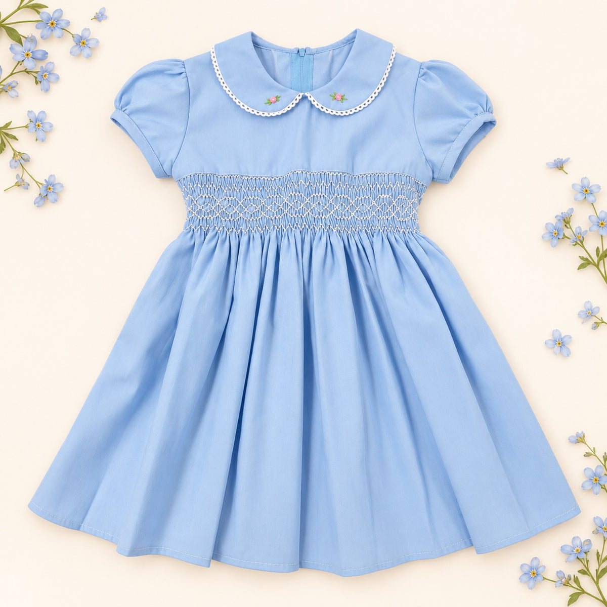 Front view of a light blue handmade 100% cotton girls' hand-smocked dress with Peter Pan collar and puff sleeves