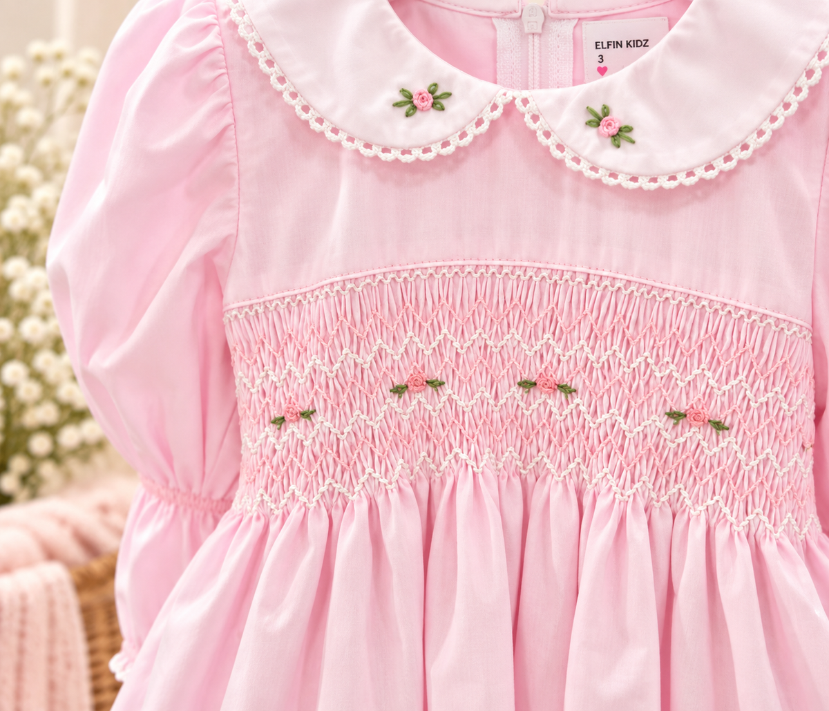 Close-up of pink smocked girls dress with Peter Pan collar, embroidered roses and detailed hand smocking